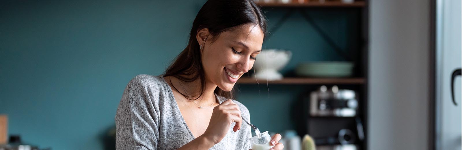 Woman smiles while eating yogurt