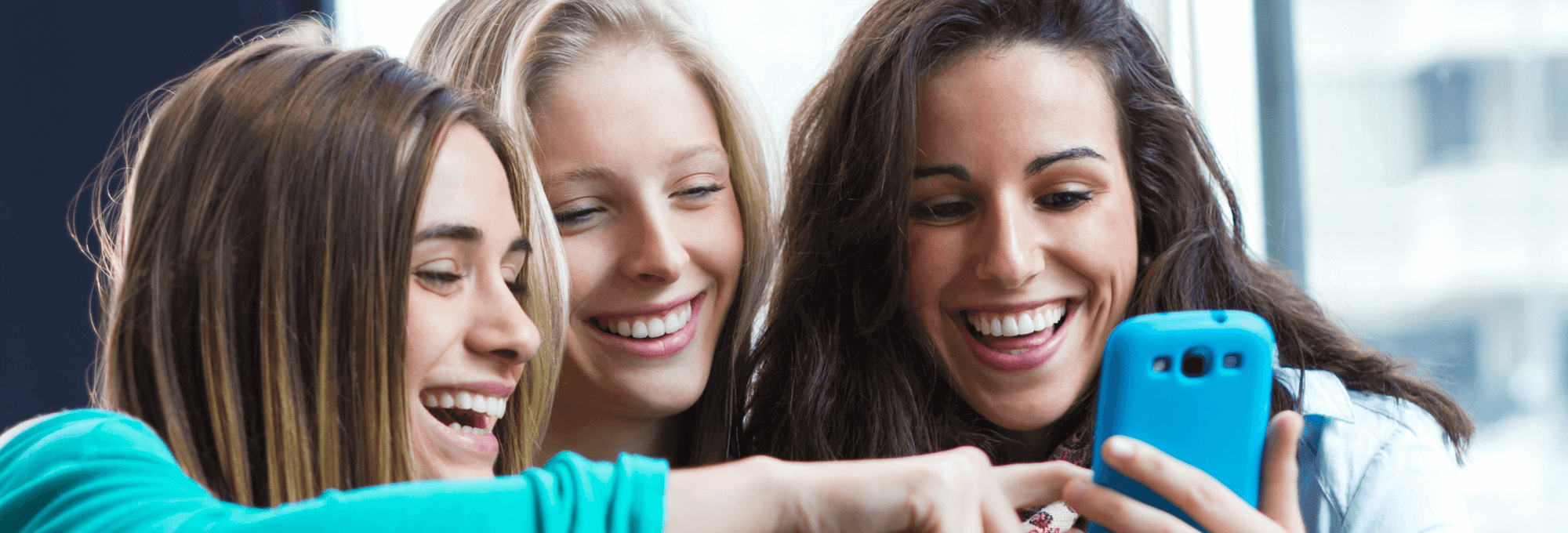 girls smiling at cell phone